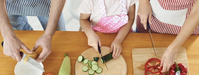 adults and child preparing vegetables